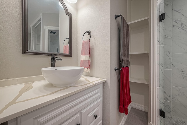 bathroom with a textured wall, vanity, and a shower stall