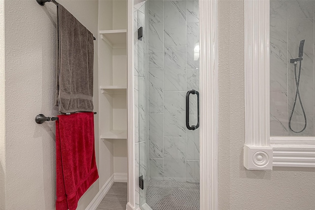 full bathroom with a textured wall, a stall shower, and baseboards