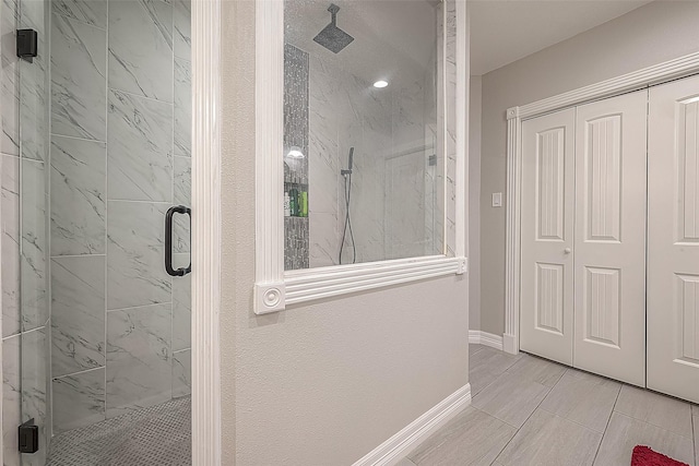 full bath featuring a marble finish shower and baseboards