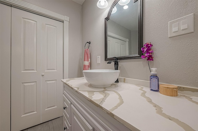 bathroom featuring a textured wall and vanity