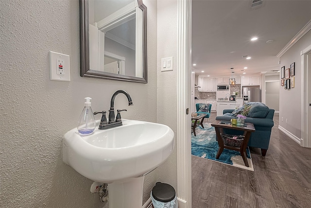 bathroom featuring crown molding, recessed lighting, visible vents, a textured wall, and wood finished floors