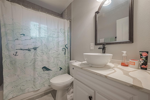 bathroom featuring toilet, a textured wall, and vanity