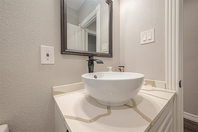 bathroom with a textured wall and vanity