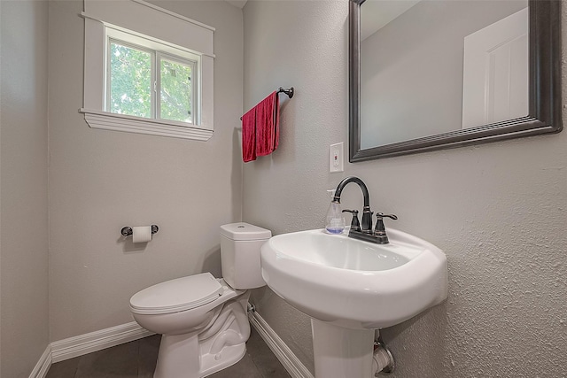 bathroom featuring a sink, toilet, and baseboards