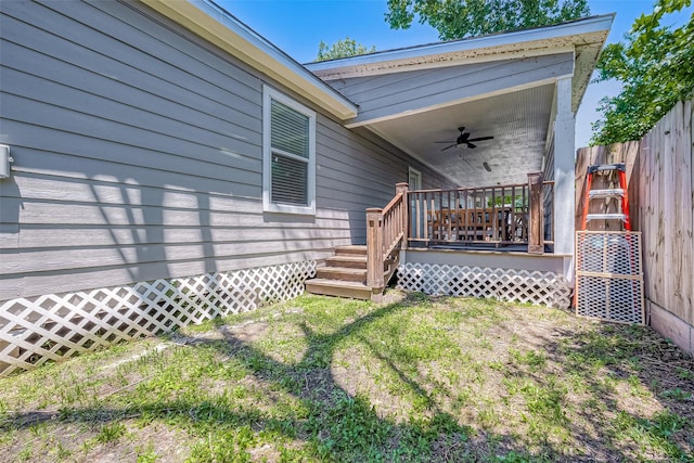 view of yard featuring ceiling fan, a deck, and fence