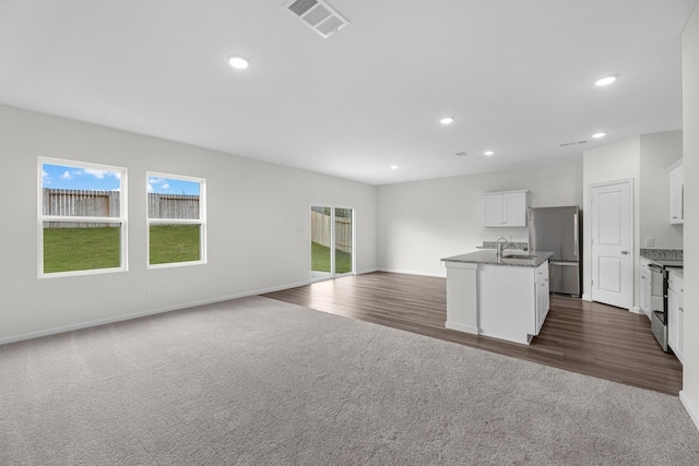 kitchen with visible vents, open floor plan, stainless steel appliances, dark colored carpet, and white cabinetry