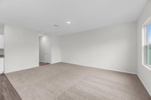 unfurnished room with recessed lighting, visible vents, dark carpet, and baseboards