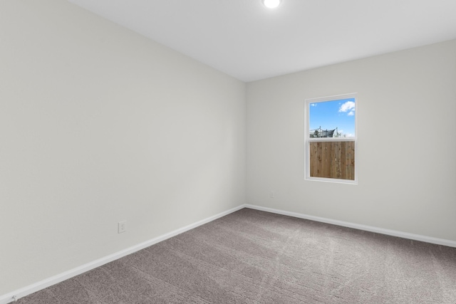 carpeted empty room featuring baseboards