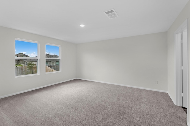 empty room with carpet floors, recessed lighting, visible vents, and baseboards