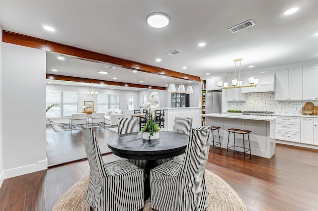 dining room featuring dark wood-type flooring, beam ceiling, visible vents, and an inviting chandelier