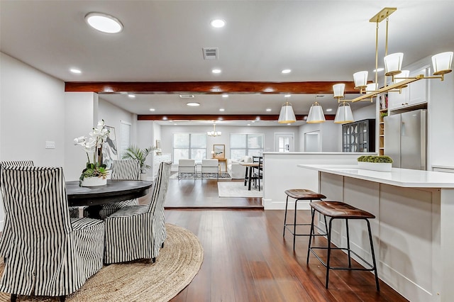 dining room with an inviting chandelier, visible vents, and beam ceiling