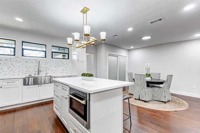 kitchen with a breakfast bar, oven, a sink, and visible vents