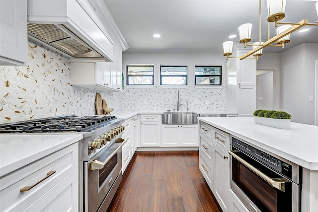 kitchen featuring appliances with stainless steel finishes, a sink, custom exhaust hood, light countertops, and backsplash