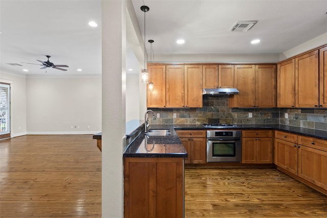 kitchen featuring tasteful backsplash, visible vents, appliances with stainless steel finishes, under cabinet range hood, and a sink