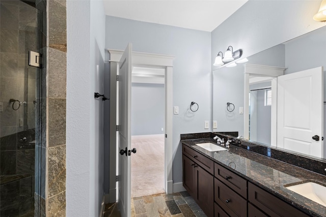 bathroom featuring a stall shower, stone finish flooring, and a sink