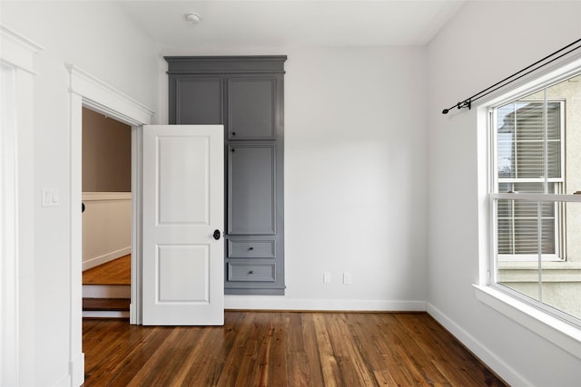 unfurnished bedroom featuring baseboards and dark wood-type flooring