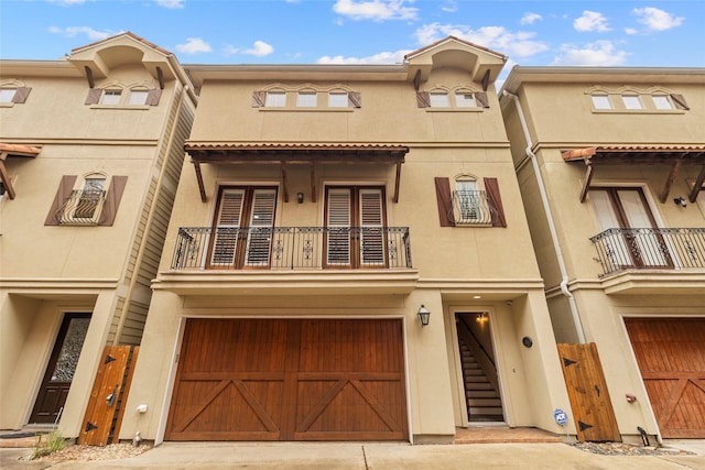 multi unit property with a garage, driveway, a balcony, and stucco siding