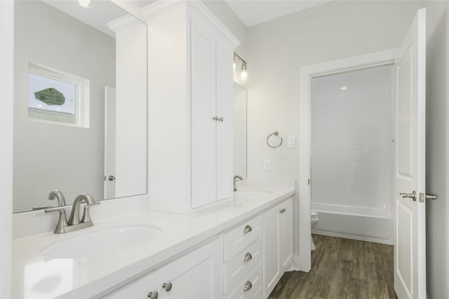 full bathroom featuring double vanity, wood finished floors, a sink, and toilet