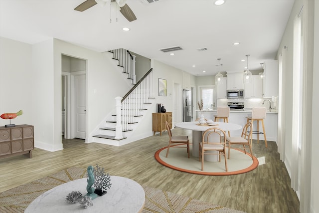 dining room with light wood-type flooring, stairs, visible vents, and recessed lighting