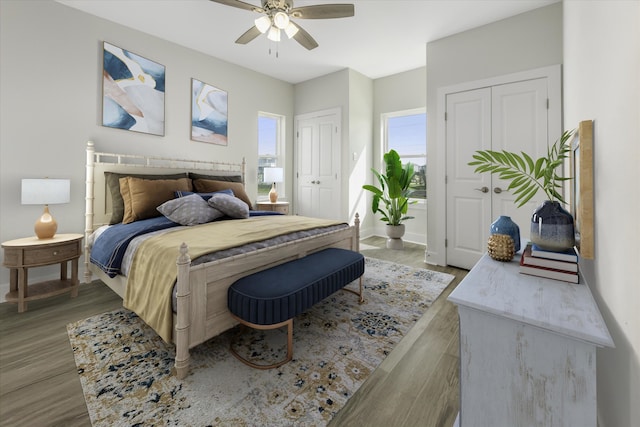 bedroom featuring baseboards, ceiling fan, light wood finished floors, and two closets