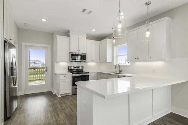 kitchen featuring a peninsula, a sink, visible vents, white cabinetry, and appliances with stainless steel finishes