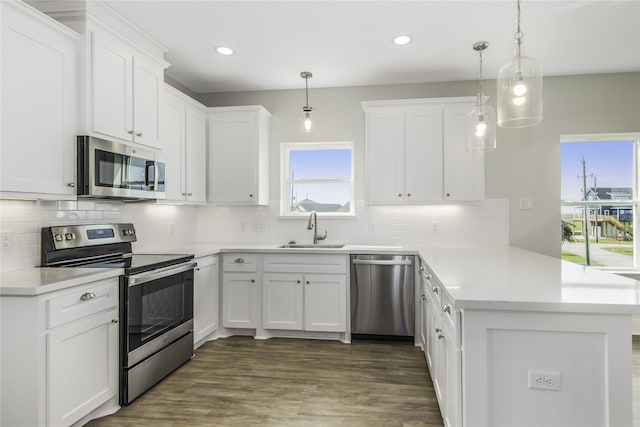 kitchen with stainless steel appliances, white cabinetry, a sink, and a peninsula