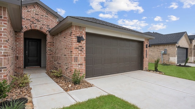 exterior space with a garage, a shingled roof, concrete driveway, and brick siding