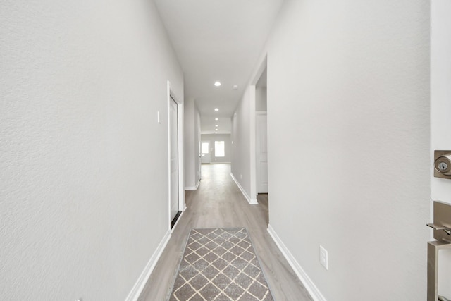 hallway with light wood-type flooring, baseboards, and recessed lighting