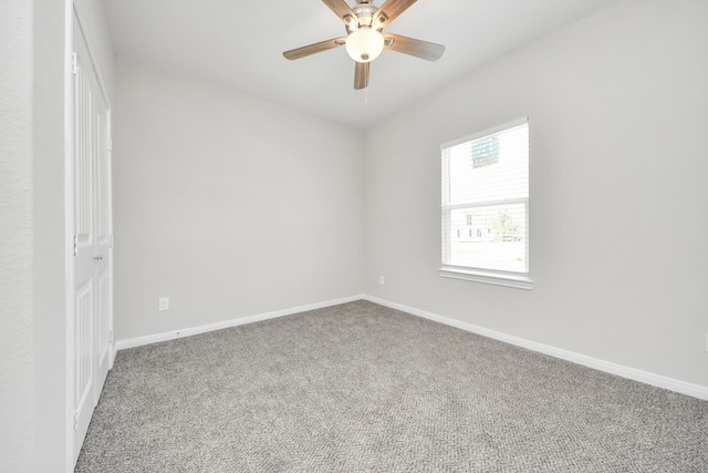 carpeted spare room with ceiling fan and baseboards