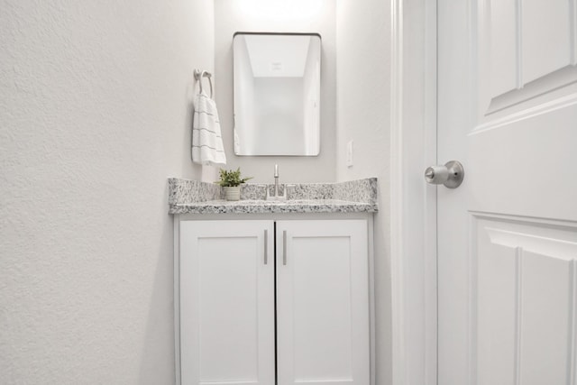 bathroom with a textured wall and vanity