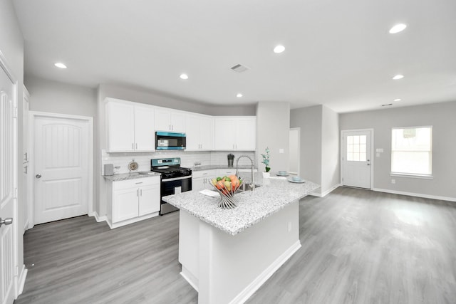 kitchen featuring light wood-style floors, tasteful backsplash, appliances with stainless steel finishes, and white cabinets