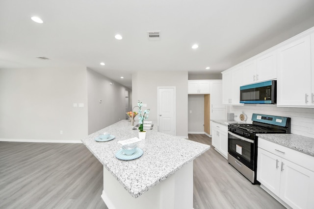 kitchen featuring light wood-style floors, stainless steel gas range oven, visible vents, and recessed lighting