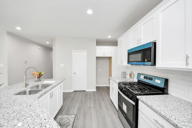 kitchen featuring a sink, white cabinetry, light wood-type flooring, stainless steel gas stove, and tasteful backsplash