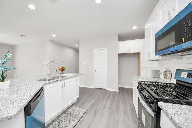 kitchen with light wood-style flooring, stainless steel appliances, a sink, white cabinets, and backsplash