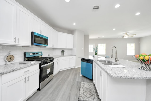 kitchen with appliances with stainless steel finishes, white cabinetry, a sink, and a center island with sink