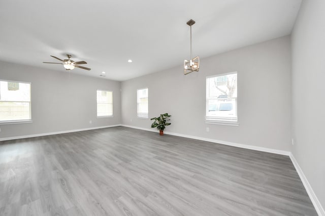 spare room featuring ceiling fan with notable chandelier, recessed lighting, wood finished floors, and baseboards