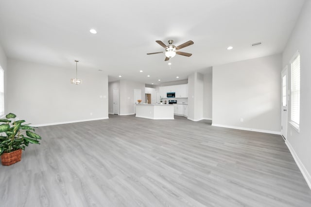 unfurnished living room with a ceiling fan, recessed lighting, light wood-style floors, and baseboards