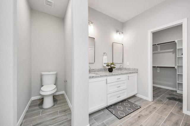 full bathroom with double vanity, visible vents, a sink, and wood finish floors