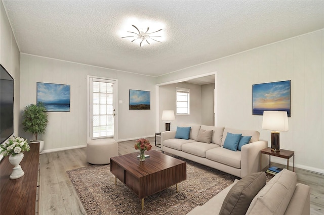 living area with wood-type flooring, a textured ceiling, and baseboards