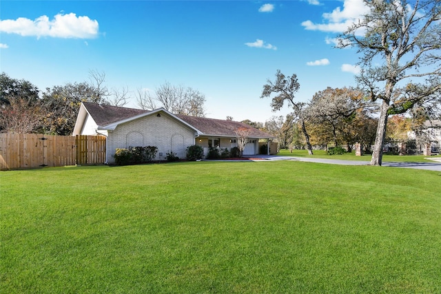 exterior space with brick siding, a yard, fence, a garage, and driveway