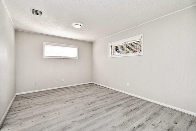 spare room with visible vents, ornamental molding, a textured ceiling, wood finished floors, and baseboards