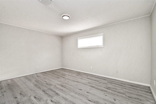 unfurnished room with visible vents, a textured ceiling, baseboards, and wood finished floors