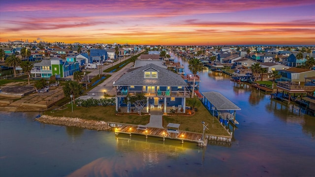 aerial view at dusk with a residential view and a water view