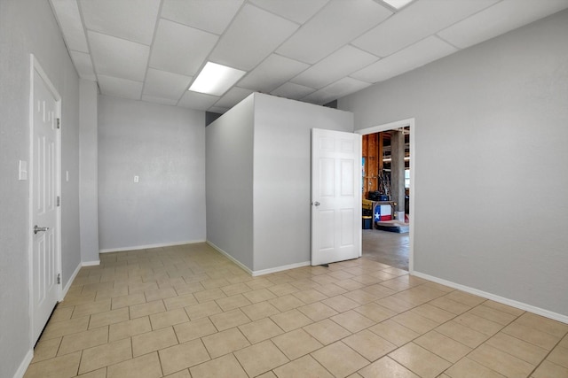 unfurnished room with a paneled ceiling and baseboards