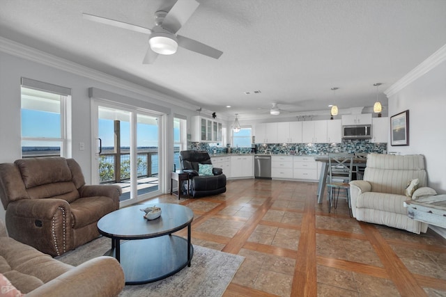 living area with ornamental molding, light tile patterned floors, a textured ceiling, and a ceiling fan