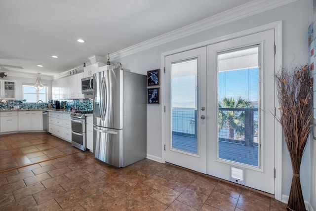 kitchen with tasteful backsplash, white cabinets, ornamental molding, stainless steel appliances, and french doors