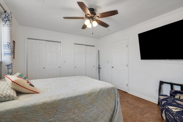 bedroom with a ceiling fan, baseboards, ornamental molding, and two closets