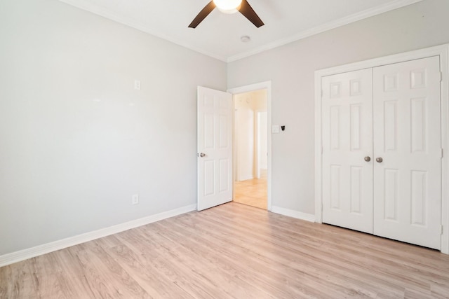 unfurnished bedroom with baseboards, ceiling fan, crown molding, light wood-type flooring, and a closet