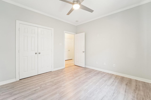 unfurnished bedroom featuring crown molding, light wood finished floors, a closet, and baseboards