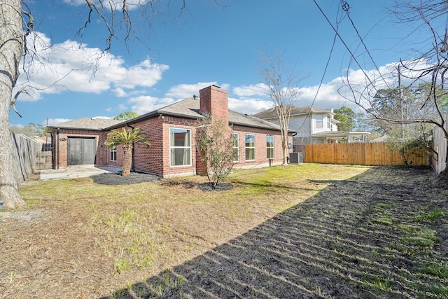 rear view of property featuring a fenced backyard, brick siding, a lawn, a chimney, and a patio area